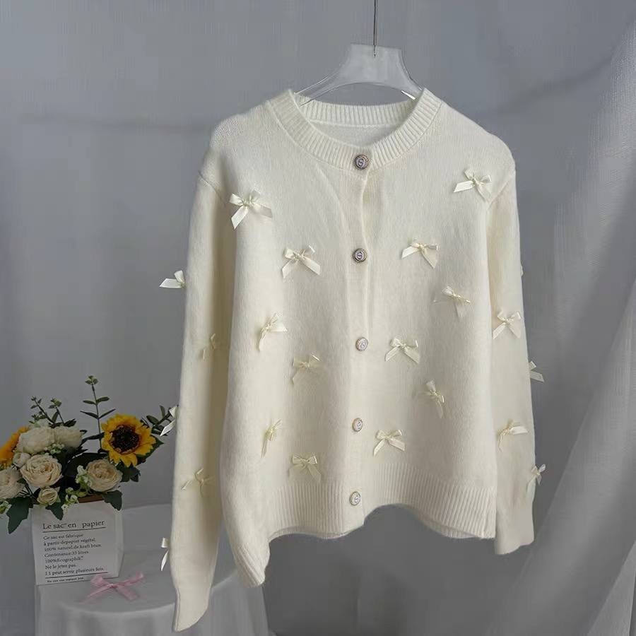 White knit cardigan adorned with delicate small bow accents and light colored buttons