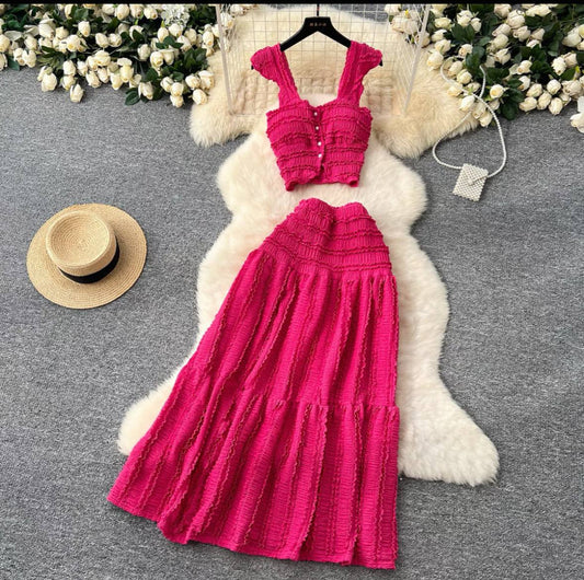 Two-piece set featuring a hot pink, smocked crop top with ruffled details and a long, tiered skirt