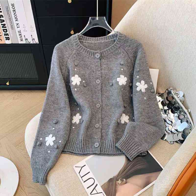 Grey crewneck knit cardigan featuring white embroidered floral details and raised pom pom textures
