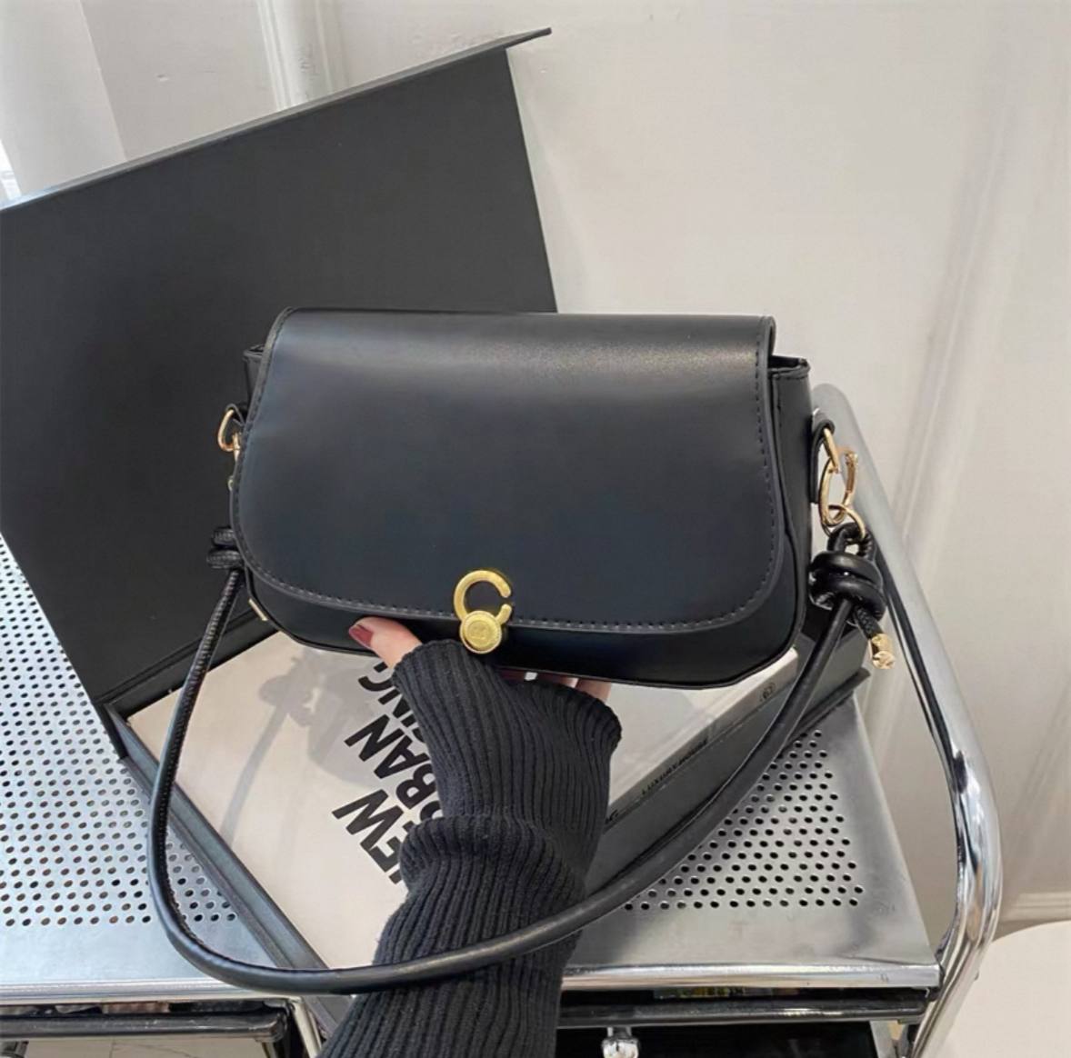 Black minimalist shoulder or crossbody bag with a gold-tone twist-lock clasp